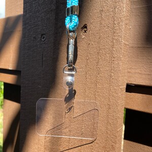 May include: A clear plastic ID badge holder with a silver clip attached to a light blue lanyard.
