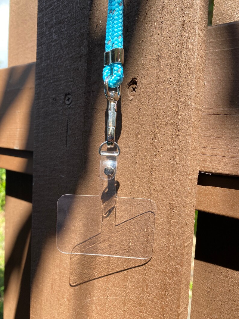 May include: A clear plastic ID badge holder with a silver clip attached to a light blue lanyard.