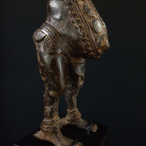 K&ouml;nnte beinhalten: Eine bronzefarbene Skulptur einer Figur mit detaillierten Schnitzereien. Die Figur hat einen runden Torso und Beine mit komplizierten Mustern am Oberk&ouml;rper. Die Skulptur ist auf einem schwarzen Sockel montiert.