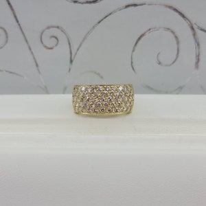 May include: A gold band ring with a wide, pave-set diamond band.