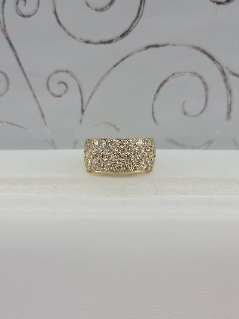 May include: A gold band ring with a wide, pave-set diamond band.