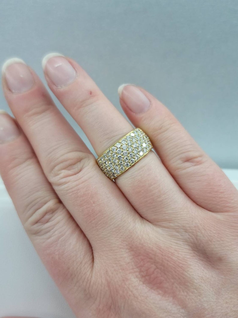 May include: A gold band ring with a wide band set with small diamonds.