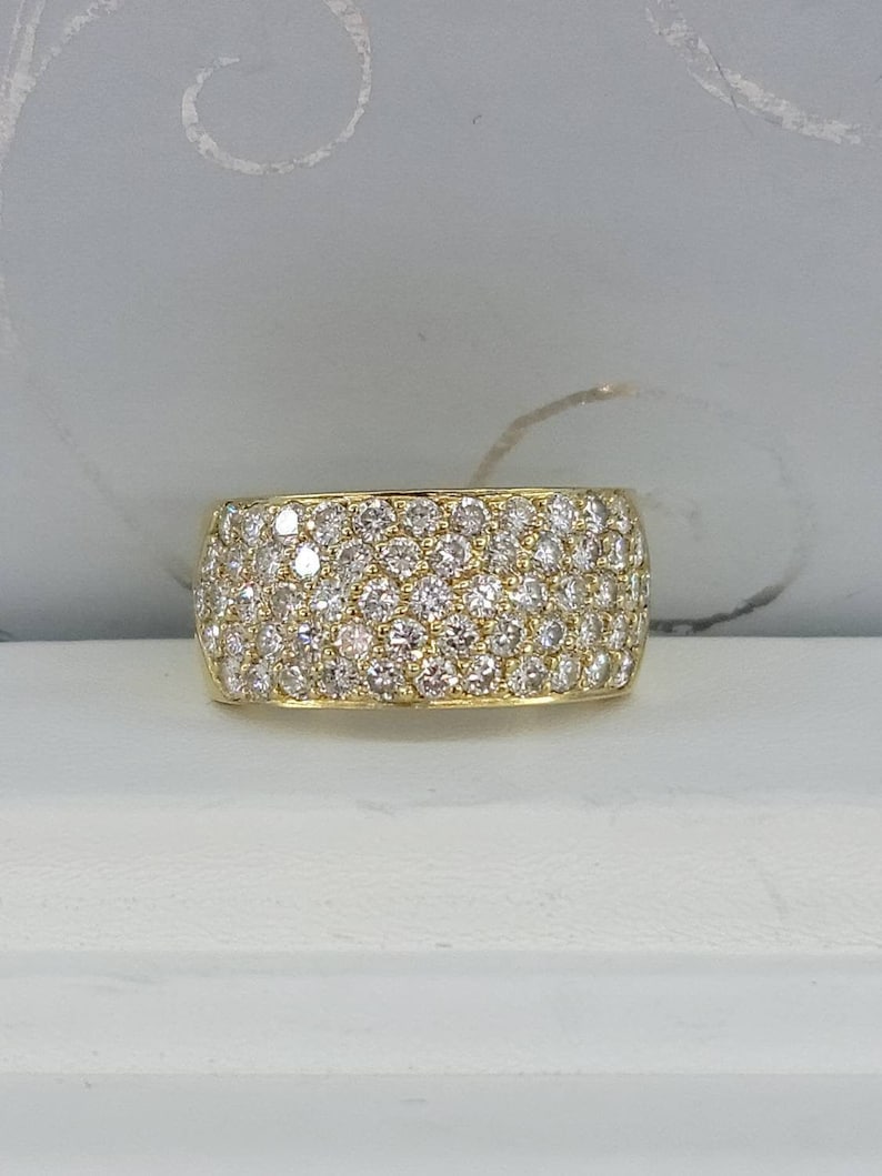 May include: A gold band ring with a wide, pave-set diamond band.