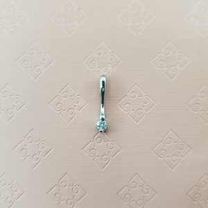 May include: A silver pendant with a single clear diamond.