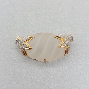 May include: A gold ring with a white frosted oval stone and two diamond-encrusted leaf accents.