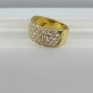 May include: A gold band ring with a wide, flat top that is completely covered in small, clear stones.