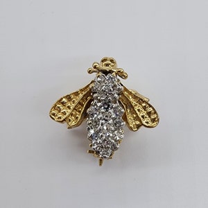May include: A gold bee brooch with a diamond-encrusted body and textured wings.