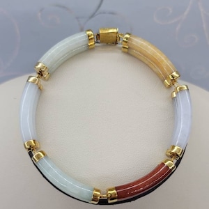 May include: A jade bracelet with gold accents. The bracelet is made of four sections of jade, each a different color: white, light green, yellow, and red.