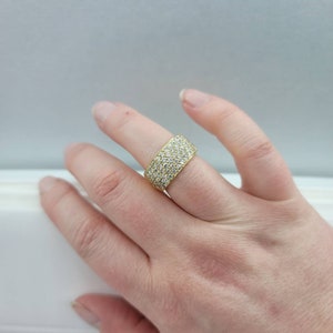May include: A gold band ring with a pave setting of small, clear diamonds.