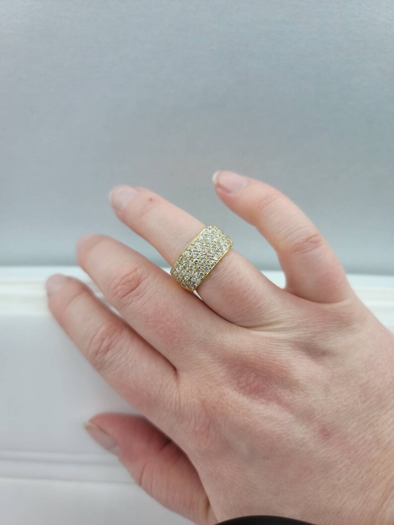 May include: A gold band ring with a pave setting of small, clear diamonds.