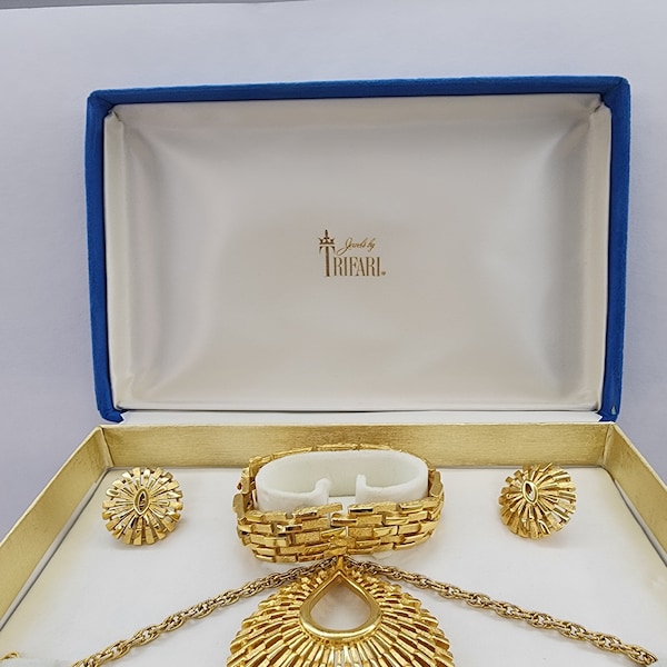 Vintage 1955-1969 Crown Trifari jewelry set with Original box. Starburst Gold tone pendant necklace with clip earrings and 7" Bracelet.