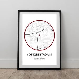 May include: Framed print of Sixfields Stadium, Northampton, featuring a circular map with a red border. The map details roads and landmarks. The stadium's name and coordinates are printed below the map.