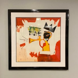 May include: Abstract art print in a black frame. The artwork features a yellow figure playing a trumpet, with a black crown and red and white paint strokes. The artwork has the text "EEE" and "CEL" in the upper left corner.