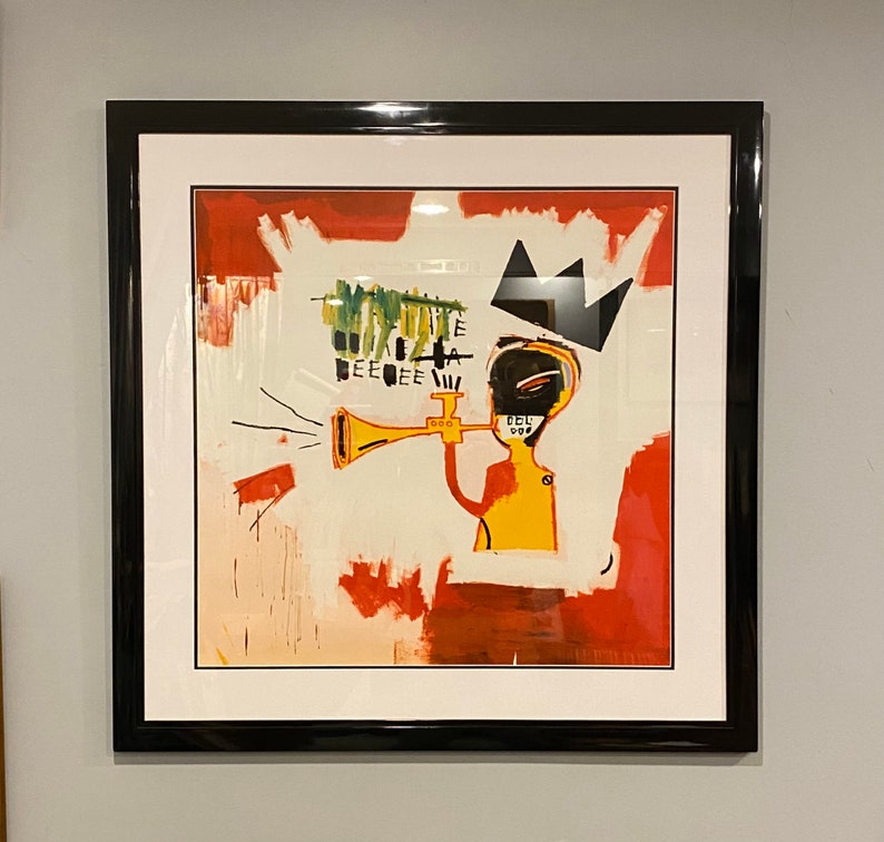 May include: Abstract art print in a black frame. The artwork features a yellow figure playing a trumpet, with a black crown and red and white paint strokes. The artwork has the text "EEE" and "CEL" in the upper left corner.