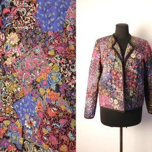 May include: A long-sleeve quilted jacket featuring a vibrant patchwork floral pattern in shades of pink, blue, gold, and black. The jacket has a collarless open front design with black trim along the edges and a straight hemline.