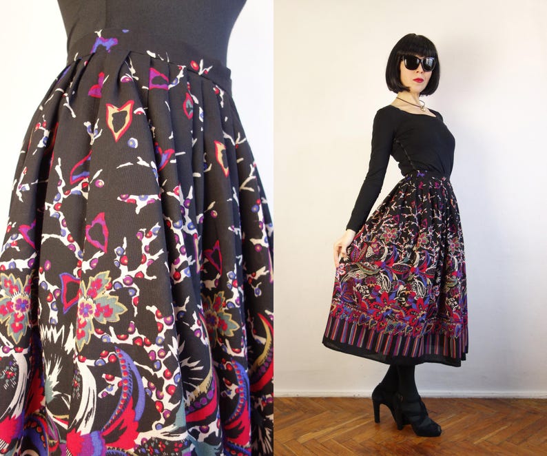 May include: A black midi skirt featuring a vibrant, multi-coloured floral and abstract pattern with shades of red, purple, blue, and white. The skirt has a high-waisted design with structured pleats that create a full, flared silhouette.