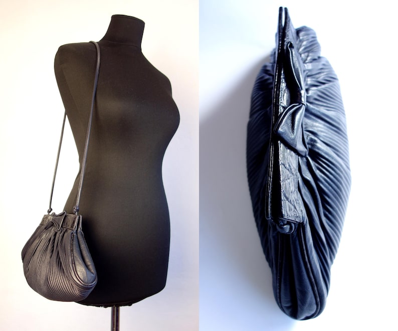 May include: Black leather shoulder bag with a pleated design. The bag has a drawstring closure and a thin shoulder strap. The bag is displayed on a black mannequin. The bag is also shown from a side view.