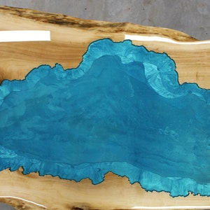 Puede incluir: Una encimera de mesa de madera con una gran incrustaci&oacute;n de resina azul turquesa de forma irregular.