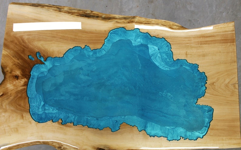 Puede incluir: Una encimera de mesa de madera con una gran incrustaci&oacute;n de resina azul turquesa de forma irregular.