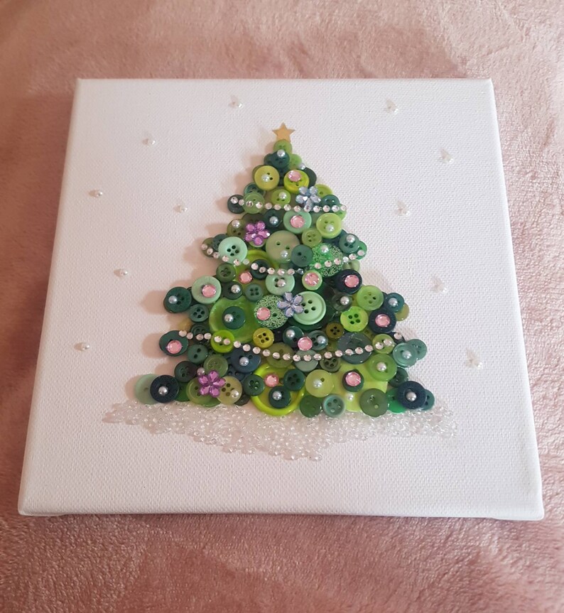 Peut inclure: Une toile blanche avec un sapin de No&euml;l en boutons verts d&eacute;cor&eacute; de boutons verts, roses et blancs, de strass et d'une &eacute;toile dor&eacute;e au sommet.