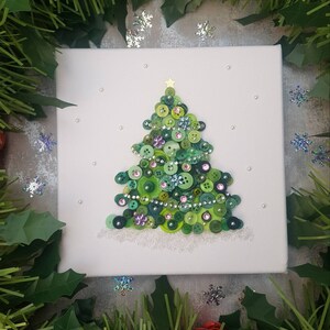 Peut inclure: Une toile blanche avec un sapin de No&euml;l en boutons verts. L'arbre est d&eacute;cor&eacute; de boutons verts, roses et bleus, ainsi que de perles argent&eacute;es et blanches. L'arbre a une &eacute;toile dor&eacute;e au sommet.