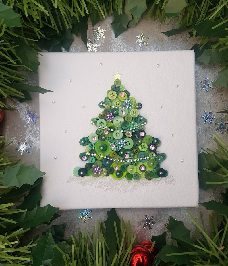 Peut inclure: Une toile blanche avec un sapin de No&euml;l en boutons verts. L'arbre est d&eacute;cor&eacute; de boutons verts, roses et bleus, ainsi que de perles argent&eacute;es et blanches. L'arbre a une &eacute;toile dor&eacute;e au sommet.