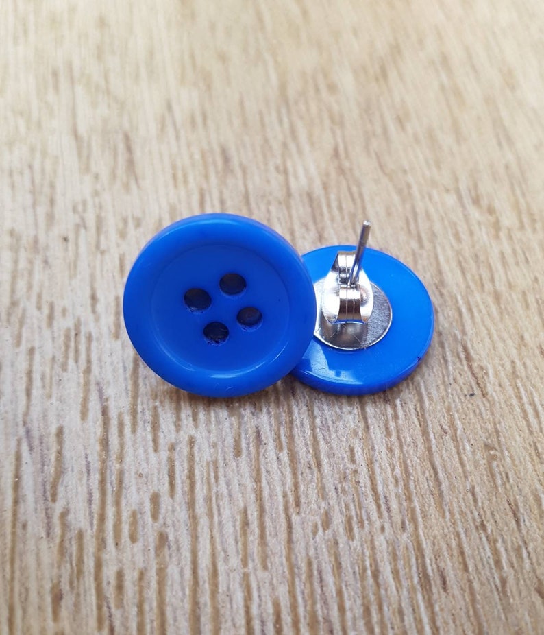May include: A pair of blue button earrings. The buttons have four holes and are attached to silver posts.