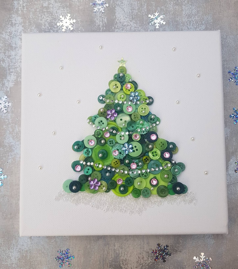 Peut inclure: Une toile blanche avec un sapin de No&euml;l en boutons verts d&eacute;cor&eacute; de boutons verts, roses et bleus, de strass et d'une &eacute;toile dor&eacute;e au sommet.