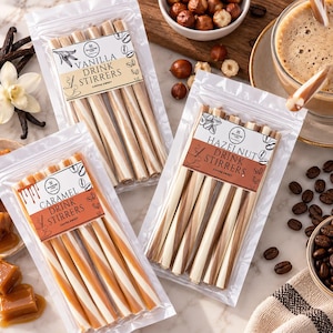 May include: Three clear plastic pouches containing cylindrical drink stirrers in vanilla, caramel, and hazelnut flavors. Each pouch features a label with the flavor name, the text Drink Stirrers, and Coffee Sweet. The stirrers are striped in white and brown.