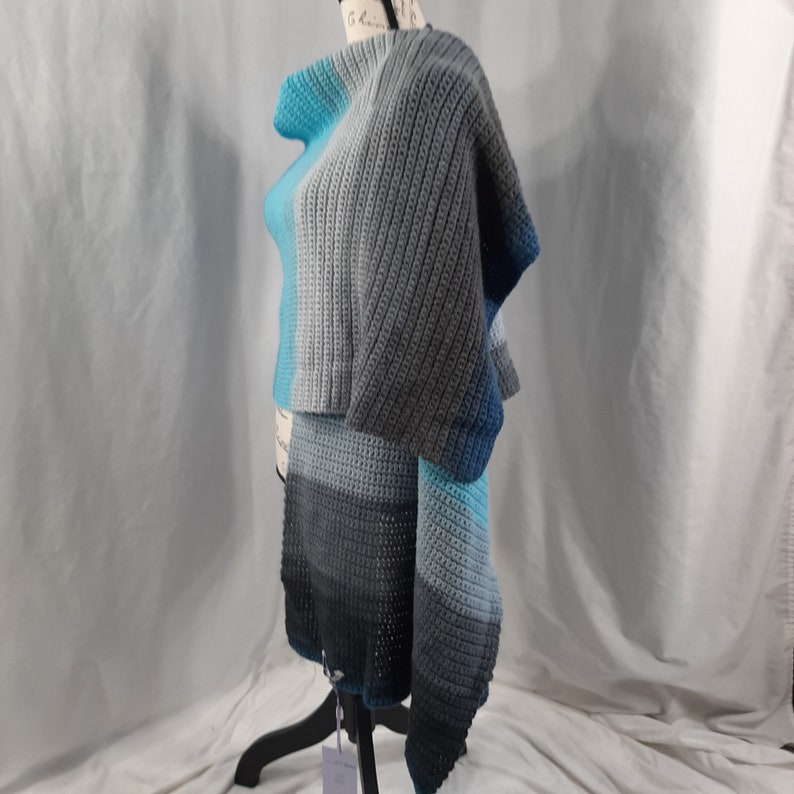 K&ouml;nnte beinhalten: Ein geh&auml;keltes Tuch in Blaut&ouml;nen und Grau. Das Tuch ist &uuml;ber eine Schaufensterpuppe gelegt und hat ein lockeres, flie&szlig;endes Design.