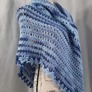 Könnte beinhalten: Ein blauer Häkel-Schal mit einem zarten Muster und einem gewellten Rand.