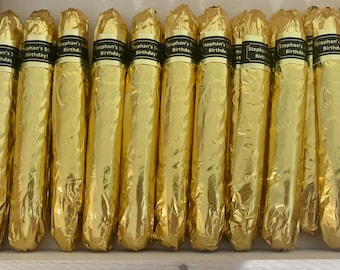 May include: A box of 10 gold-wrapped chocolate cigars with black labels that say "Stephan's 50th Birthday!"
