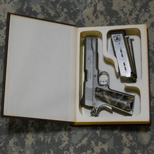 May include: A white ceramic mug with a black handle and the text "But First, Coffee" in a handwritten style. The mug is likely for hot beverages and sits on a white surface.