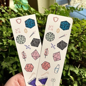 May include: Two white bookmark cards with a variety of colorful dice and other fantasy-themed illustrations. The text "ROSE PAPER STUDIO" is printed on each card.