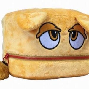 Op de afbeelding: Een cilindervormig, geel opbergtasje van pluche met een cartoongezicht met halfgesloten ogen en twee kleine oortjes aan de bovenkant. Het tasje heeft een horizontale rode ritssluiting in het midden en een kleine, pluizige gele pompon.