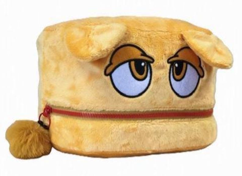 Op de afbeelding: Een cilindervormig, geel opbergtasje van pluche met een cartoongezicht met halfgesloten ogen en twee kleine oortjes aan de bovenkant. Het tasje heeft een horizontale rode ritssluiting in het midden en een kleine, pluizige gele pompon.