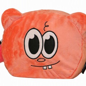 Op de afbeelding: Een oranje pluche etui met een cartoongezicht met grote witte ogen, zwarte pupillen, een kleine neus en twee zichtbare tanden. Het etui heeft afgeronde oren en een felroze pompon bevestigd aan de ritssluiting aan de zijkant.