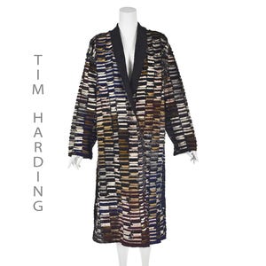 May include: A long black and white patterned coat with a black collar. The coat has a geometric pattern with horizontal stripes and squares.