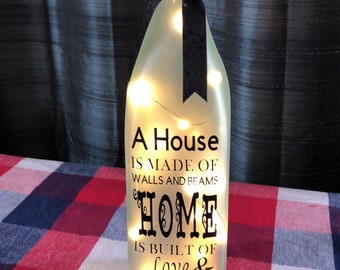 A House is made of bricks and beams A home is made of Love and Dreams Decorated wine bottle with lights