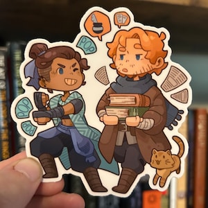 May include: A sticker featuring two cartoon characters, one with a determined expression and the other holding books. The sticker has a white border and includes speech bubbles with the word "POP" and images of a pen and books.