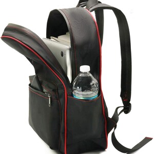 Puede incluir: Mochila negra con ribetes rojos, abierta para revelar un port&aacute;til y una botella de agua en un bolsillo lateral.