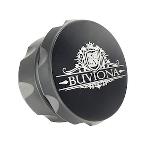May include: A grey metal grinder with a black lid featuring a silver engraved logo that says "Buviona". The logo includes a crest with a crown and floral accents.