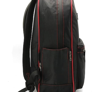 Puede incluir: Mochila negra con ribetes rojos y un bolsillo con cremallera en el lateral. La mochila tiene un panel trasero de malla y correas ajustables.