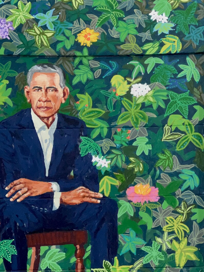 Puede incluir: Una pintura de un hombre con un traje azul oscuro sentado en una silla de madera. El fondo es un patr&oacute;n de hojas verdes y azules con flores rosas, amarillas y blancas.