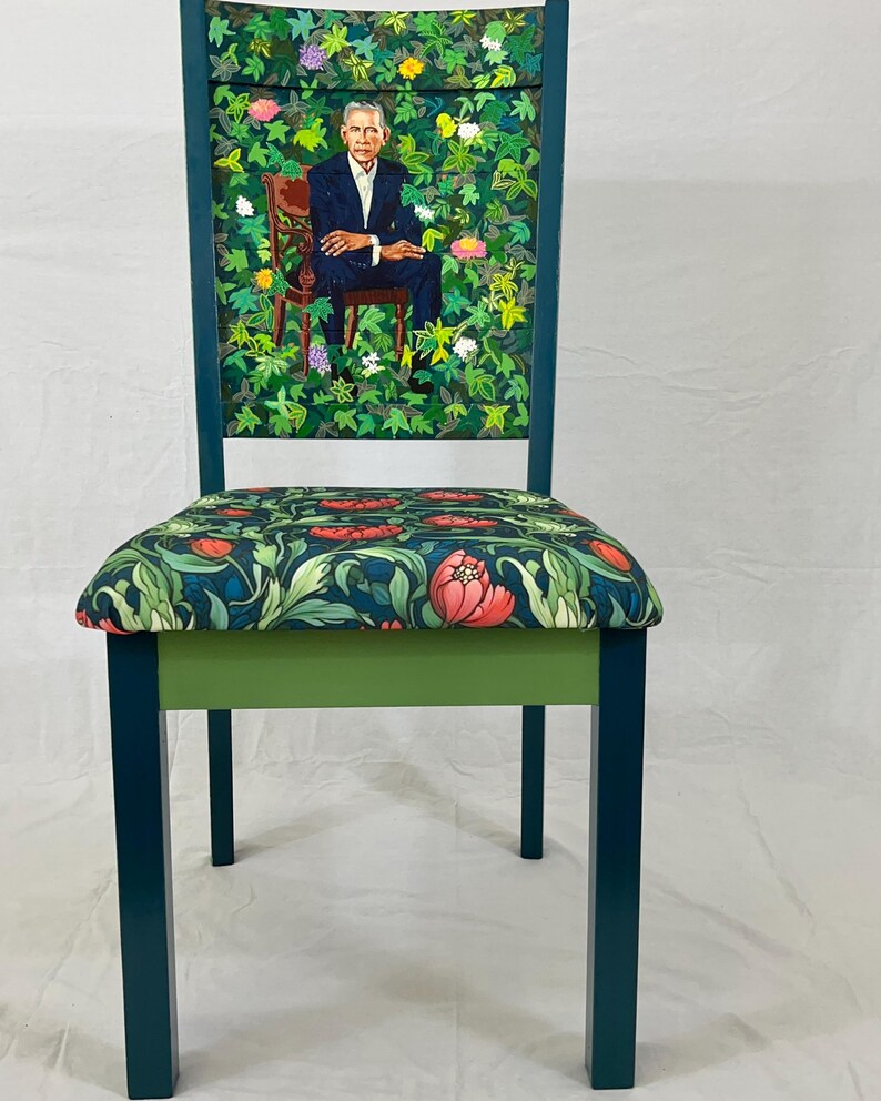 Puede incluir: Una silla azul verdosa con un asiento estampado floral verde y un respaldo verde con una pintura de un hombre con traje sentado en un jard&iacute;n.
