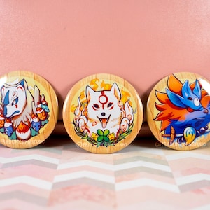 May include: Three round buttons with a wooden background and colorful illustrations of foxes. The foxes are depicted in different poses and with different expressions. The buttons are perfect for adding a touch of whimsy to any project.