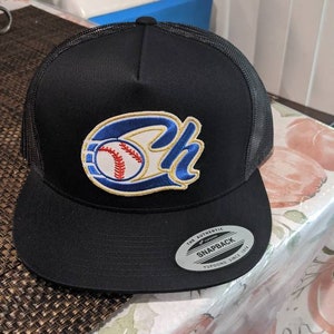 May include: Black baseball cap with a mesh back and a flat brim. The cap features a baseball-themed logo with the letters "SH" in blue and gold, and a baseball in the center. The cap has a snapback closure.