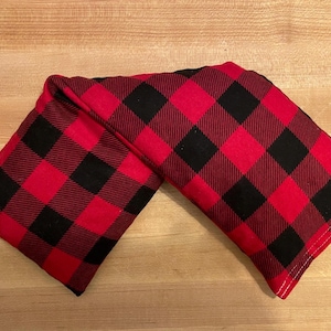 May include: Red and black buffalo plaid fabric eye pillow. The pillow is folded in half and the fabric is soft and plush.