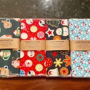 May include: Four reusable flannel towels, each with a different festive pattern. Designs include mugs, snowmen, ornaments, and gingerbread men. Each towel measures 10 x 12 inches and is made of 100% cotton flannel.