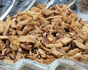 May include: Close-up of dried ginger pieces in a clear, decorative glass dish. The ginger is a light brown color and appears to be cut into small, irregular pieces. The dish has a unique, wavy design.